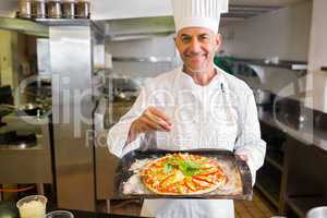 Confident male chef holding cooked food in kitchen