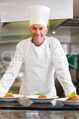 Confident male chef with cooked food in kitchen