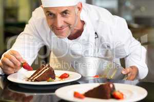Smiling male pastry chef decorating dessert in kitchen