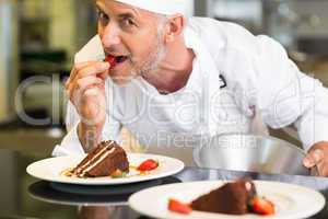 Smiling male pastry chef eating strawberry by dessert