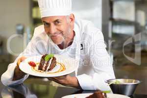 Smiling male pastry chef with dessert in kitchen