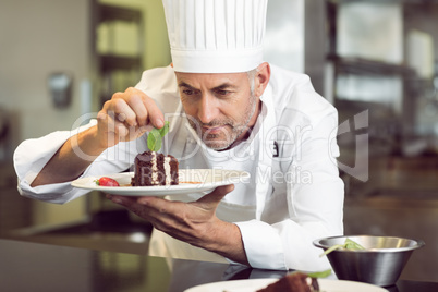 Concentrated male pastry chef decorating dessert in kitchen