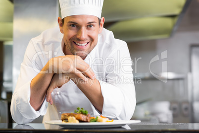 Smiling male chef with cooked food in kitchen