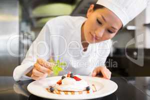 Concentrated female chef garnishing food in kitchen