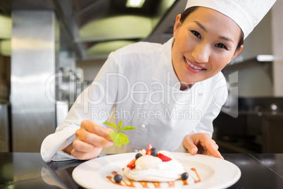 Smiling female chef garnishing food in kitchen