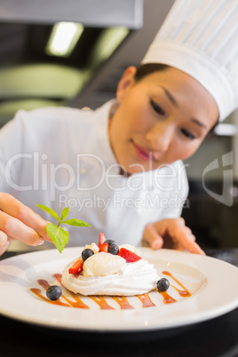 Concentrated female chef garnishing food