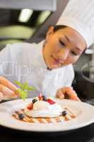 Concentrated female chef garnishing food