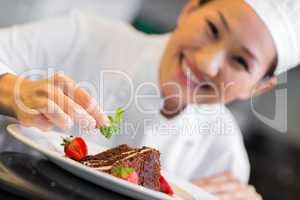 Smiling female chef garnishing food
