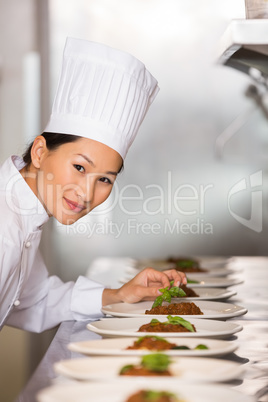 Smiling female chef garnishing food in kitchen