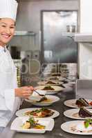 Smiling female chef garnishing food in kitchen