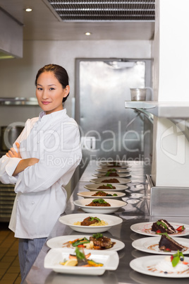 Confident chef besides cooked food in row at kitchen