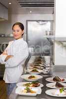 Confident chef besides cooked food in row at kitchen