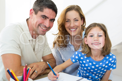 Parents assisting daughter in coloring at home
