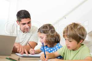 Father with laptop assisting children drawing