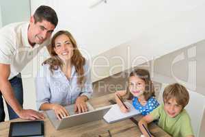 Children coloring while parents using laptop