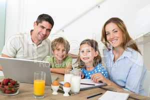 Portrait of family using laptop while having breakfast
