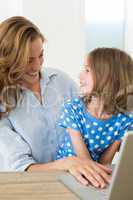 Smiling mother and daughter using laptop