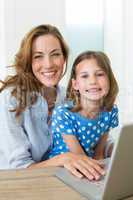 Girl and mother using laptop