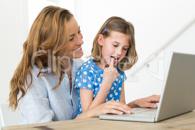 Mother teaching daughter to use laptop