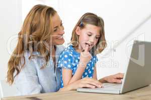 Mother teaching daughter to use laptop