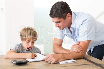 Son doing homework while father standing by