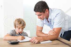 Son doing homework while father standing by