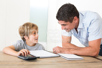 Father looking at son doing homework