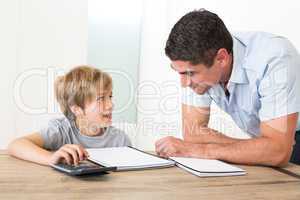 Father looking at son doing homework