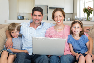 Family with laptop sitting on sofa