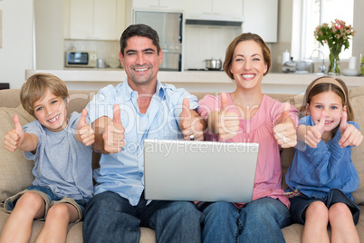 Family with laptop gesturing thumbs up on sofa Family with laptop gesturing thumbs up on sofa