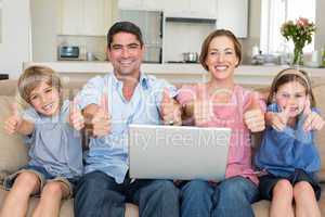 Family with laptop gesturing thumbs up on sofa