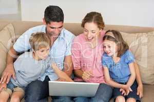 Family using laptop together on sofa