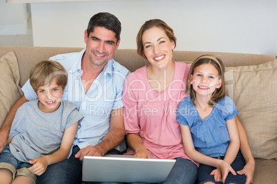 Parents and children with laptop on sofa