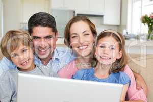 Smiling family with laptop in house