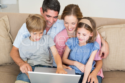 Loving family using laptop together on sofa