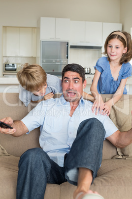 Children scaring father watching television