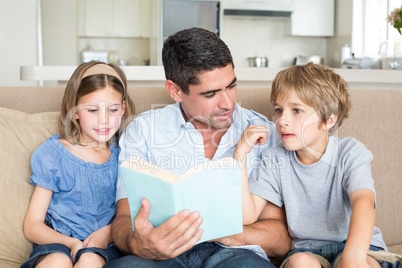 Father teaching children on sofa