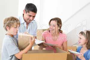 Family unpacking cardboard box in house