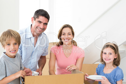 Happy family unpacking cardboard box in house