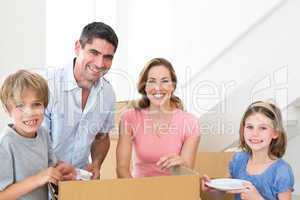 Happy family unpacking cardboard box in house