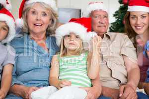 Happy multigeneration family wearing santa hats on the couch