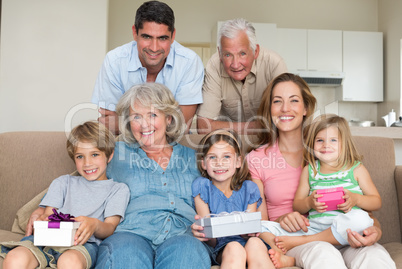 Siblings holding gifts with family in living room