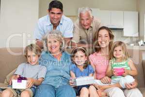 Siblings holding gifts with family in living room