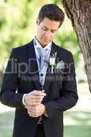 Groom adjusting sleeve at garden