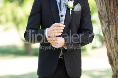 Groom adjusting sleeve in garden