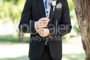 Groom adjusting sleeve in garden