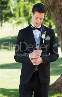Handsome groom adjusting sleeve in garden