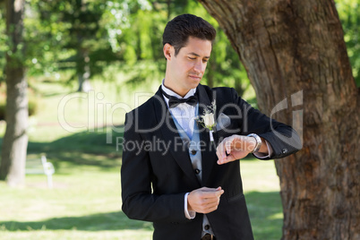 Attractive groom checking time in garden