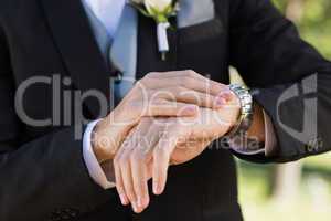 Midsection of groom checking time