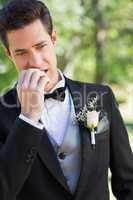 Young groom biting nails in garden